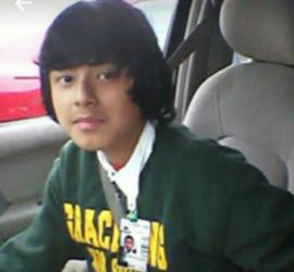 Hispanic high school teen wearing school sweatshirt sitting in car