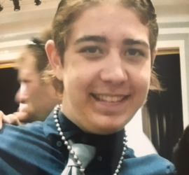 Teenage boy with blonde hair wearing a blue shirt and tie