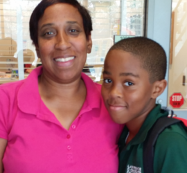 African American mother wearing a pink shirt and her elementary age son wearing a green shirt and backpack