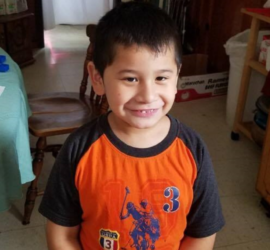 Hispanic elementary age boy wearing orange and blue polo shirt