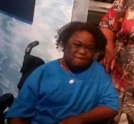 African American Teenage Boy wearing blue shirt and seated in a wheelchair