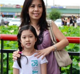 Asian mother and elementary age daughter standing in front of a garden