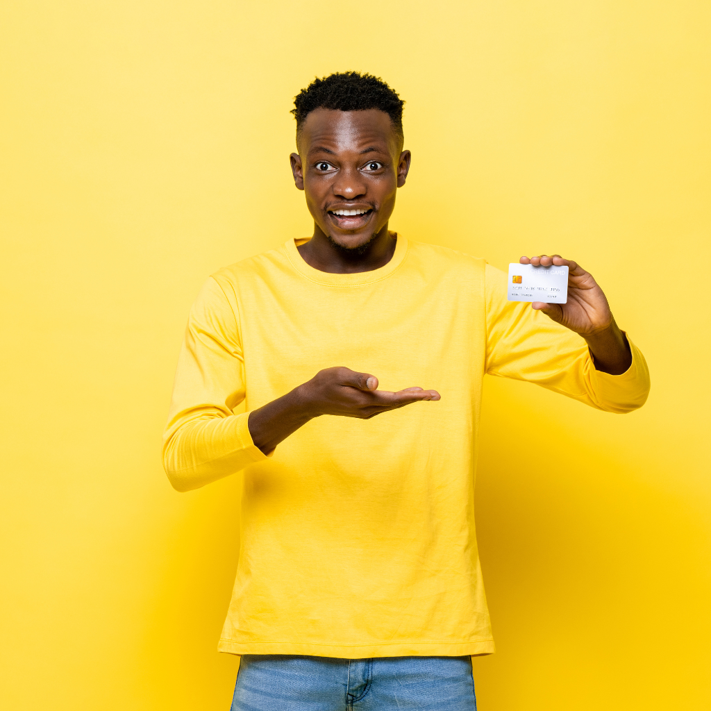 Black youth holding a credit card in one hand and pointing with the other hand.